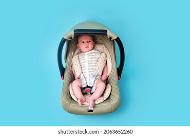 Baby In Infant Car Seat On Blue Studio Background. Carrier For Transporting Newborn Babies In A Chair