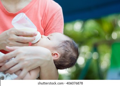 Baby Infant Drinking Milk Form Bottle On Mother Hand. Breastfeeding.