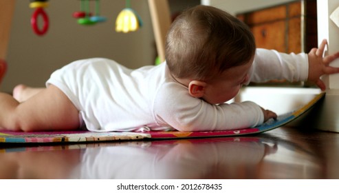 Baby Infant Lying On Play Mat In Living Room Reaching Out For Object At Home