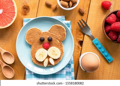 Baby Or Kid Breakfast Pancake In Shape Of Dog. Funny Breakfast For Kids With Pancake, Fruits And Boiled Egg On A Wooden Table. Top View