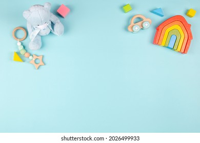 Baby kids toy for children with teddy bear, wooden rainbow house, car, organic teether, colorful blocks on light blue background. Top view, flat lay Stock Photo