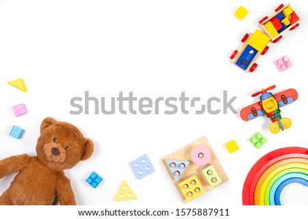 Baby kids toys background. Teddy bear, wooden educational stacking color recognition puzzle toy, wooden train, teddy bear and colorful blocks on white background. Top view, flat lay