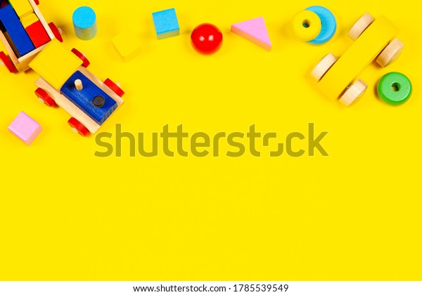 Baby kids toys\
background. Toy train, wooden car and colorful blocks on yellow\
background. Top view, flat\
lay