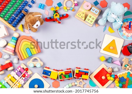 Baby kids toys frame. Colorful educational wooden plastic and fluffy toys for children on gray background. Top view