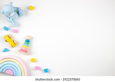 Baby kids toys frame on white background. Teddy bear and wooden educational toys on desk. Top view. Flat lay. Copy space for text