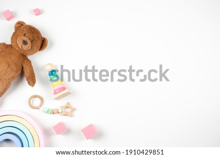 Baby kids toys frame on white background. Teddy bard and wooden educational toys on desk. Top view. Flat lay