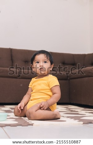 baby kneeling in the living room of the house watching