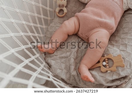 Baby is laying on a blanket with a toy giraffe in its mouth. The baby is wearing a pink outfit