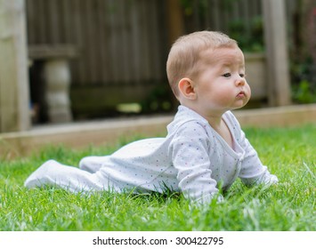 A baby laying on the grass, having tummy time