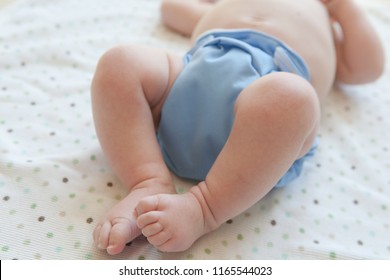 Baby Laying On Their Back Wearing A Blue Cloth Diaper.