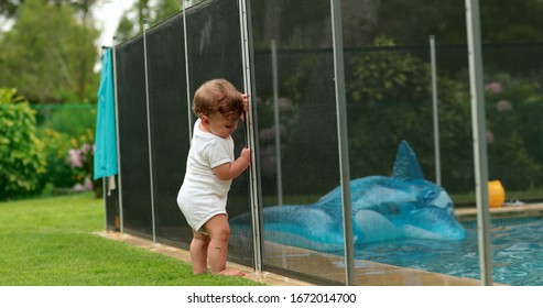 
Baby Leaning On Swimming Pool Fence Protection. Infant Standing On Safety Gate