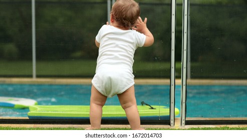 
Baby Leaning On Swimming Pool Fence Protection. Infant Standing On Safety Gate