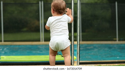 
Baby Leaning On Swimming Pool Fence Protection. Infant Standing On Safety Gate