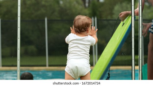 
Baby Leaning On Swimming Pool Fence Protection. Infant Standing On Safety Gate