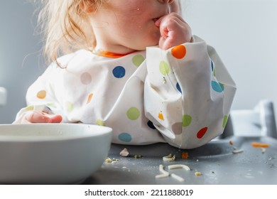 Baby Learning To Eat With Hands And Protective Clothing