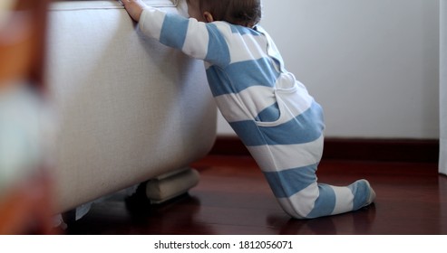 Baby Learning To Stand Up By Leaning On Home Sofa Couch. Infant Child Development.