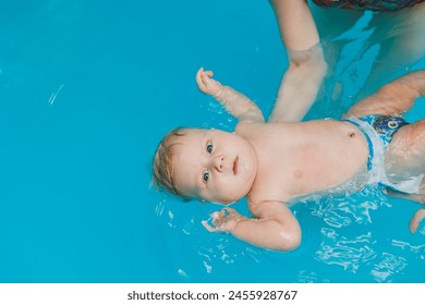 A baby learns to swim with a coach in the pool. Swimming pool for babies. - Powered by Shutterstock