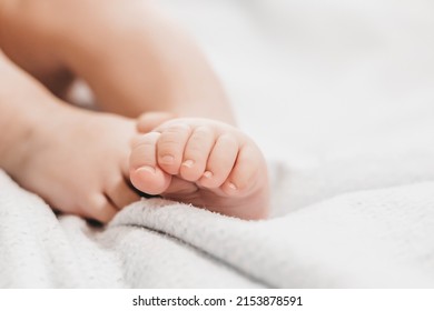 Baby Legs Lie On The Bed On A White Background. Close Up. Copy Space. Baby Foot Care