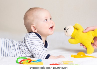 The Baby Lies On His Stomach, Smiles And Looks At Dad, Who Hands Him A Toy