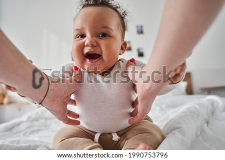 Baby looking at the camera while playing with his parents at the blanket