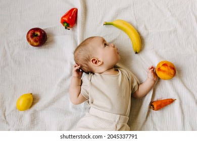 Baby Lying Among Different Fruits And Vegetables. Food Diversification Concept.