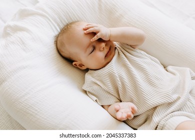 Baby Lying In A Baby Nest, Making A Facepalm Gesture.