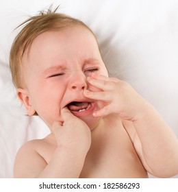 Baby Lying On A White Pillow And Crying Teething