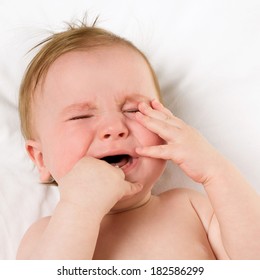 Baby Lying On A White Pillow And Crying Teething