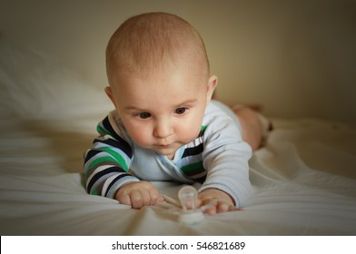 Baby Lying Purposefully Reaching For A Dummy