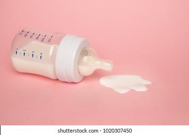 Baby Milk Bottle On A Pink Background With Neagtive Space. Spill