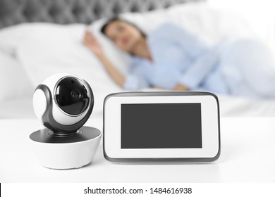 Baby Monitor And Camera On Table Near Bed With Woman In Room. Video Nanny