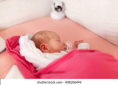 Baby monitor recording cute baby girl sleeping in bed.