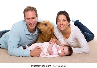 Baby Mother And Father Happy Family With Golden Retriever Dog On Carpet