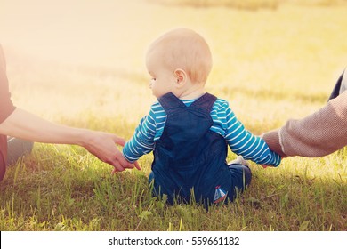 Baby With Mother And Father Holding Hands On The Nature