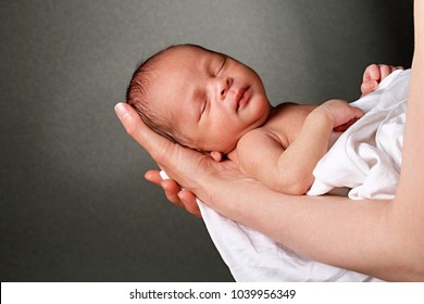 baby in mother's arms and wrapped up in white blanket just been cared for after having a good sleep in bed stock photograph stock photo