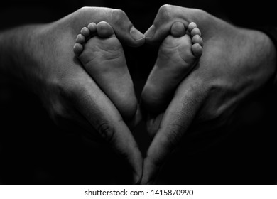 Baby newborn feet in fathers hands