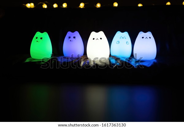 Baby night lamp, five nightlights in a row,\
different colors. Children\'s night lights. Night shooting. Several\
lamps on the couch. Front\
view.