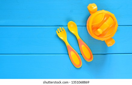 Baby Nutrition Concept Background. Children Fork, Spoon And Feeding Bottle On A Wooden Table. Top View.