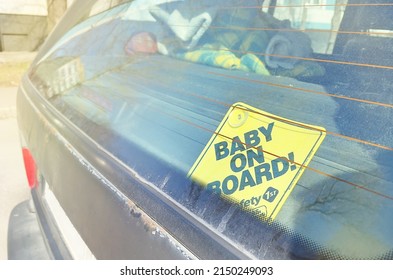Baby on board sign close-up. Yellow Baby On Board sticker on car back window. Safety first. Kid passenger. Child in a car warning sign. - Shutterstock ID 2150249093