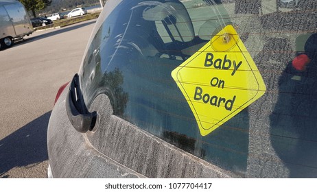 baby on board traffic yellow sign stuck  on the rear car glass