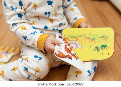 Baby Open Picture Book With Curiosity As Sit On Floor