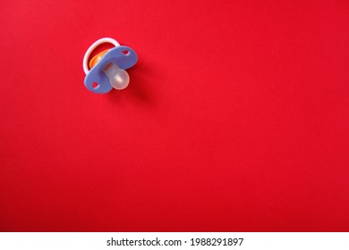 Baby Pacifier On A Red Background, Top View, Place For An Inscription