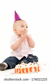 A Baby In A Party Hat Eating Cake.