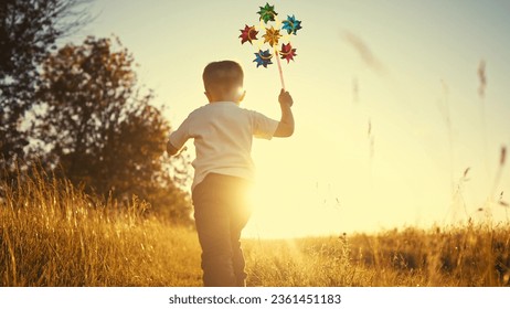 baby pinwheel. little boy silhouette plays with windmill a toy wind in park. happy family childhood dream concept. boy play spinner toy glare of the sun at sunset in fun cheerful park - Powered by Shutterstock