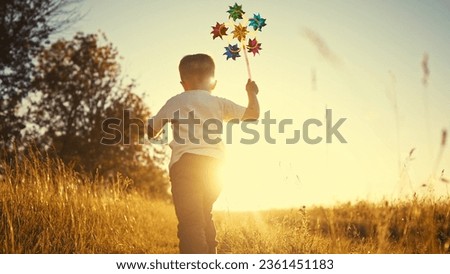 baby pinwheel. little boy silhouette plays with windmill a toy wind in park. happy family childhood dream concept. boy play spinner toy glare of the sun at sunset in fun cheerful park