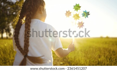 baby pinwheel. little girl silhouette plays with windmill a toy wind in park. happy family childhood dream concept. girl play fun spinner toy glare of the sun at sunset in cheerful park