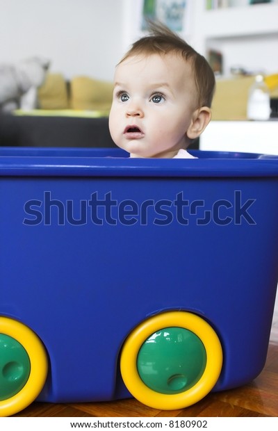 Baby\
in a plastic tray playing- pretending to drive a\
car