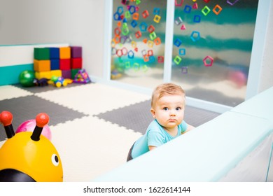 Baby Playing With Colorful Toys In Play Area