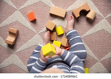 A Baby Playing With Colorful Wooden Blocks. Overhead View