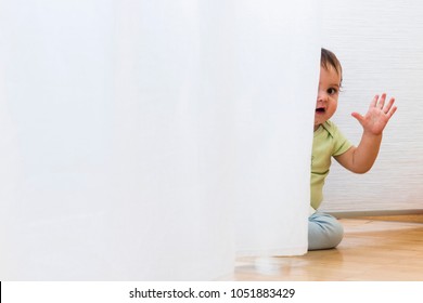 baby playing and hiding with white curtains